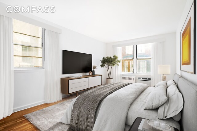 bedroom with radiator, baseboards, and wood finished floors