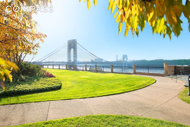 view of community featuring a water view, a lawn, and fence