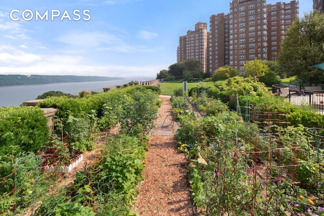 view of property's community featuring a water view, a garden, fence, and a city view