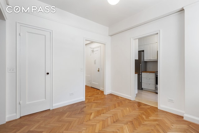 unfurnished bedroom featuring freestanding refrigerator and baseboards