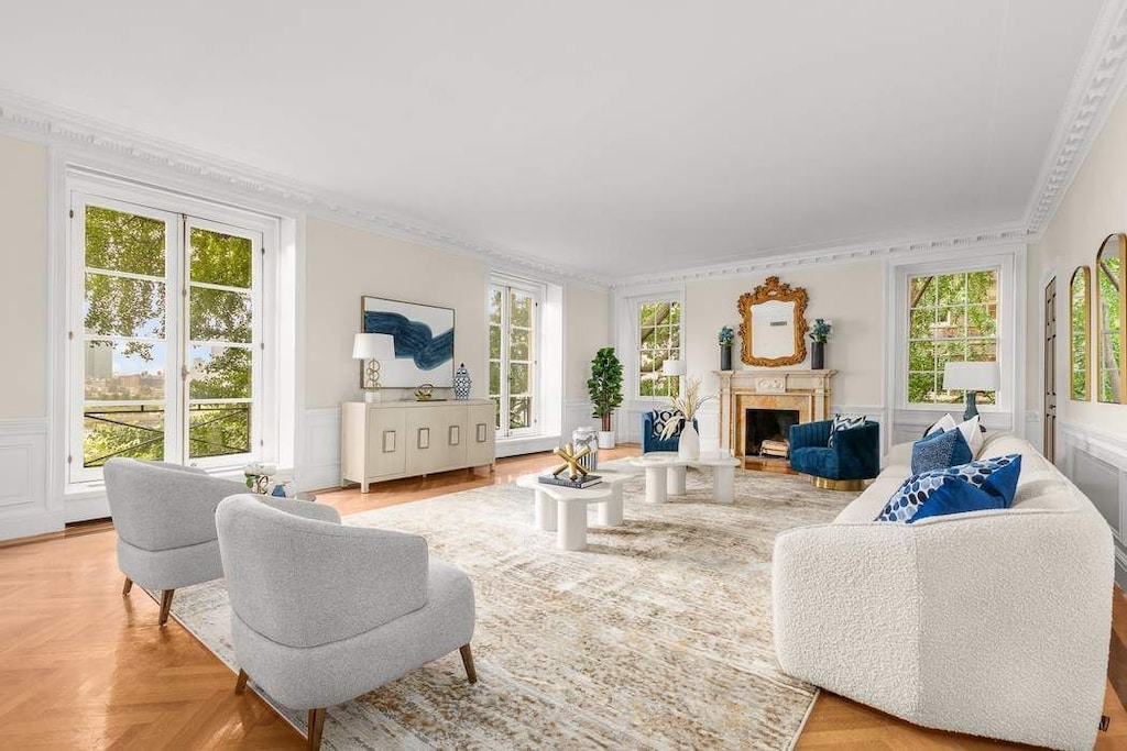 living room featuring crown molding, a decorative wall, a fireplace, and wainscoting