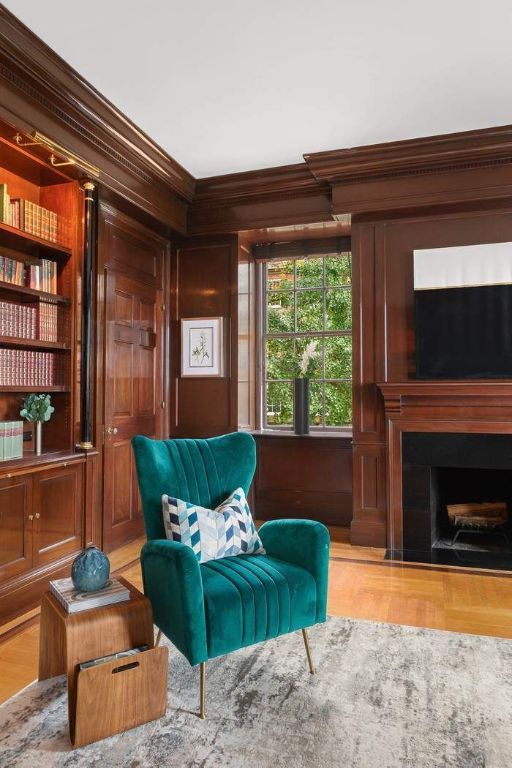 sitting room with crown molding, built in shelves, light wood-type flooring, and wood walls