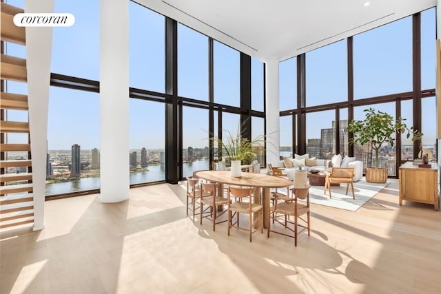 dining room featuring a water view, a high ceiling, expansive windows, and light wood-style flooring