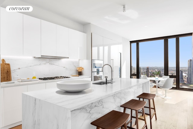 kitchen with white cabinets, a sink, decorative backsplash, gas stovetop, and modern cabinets