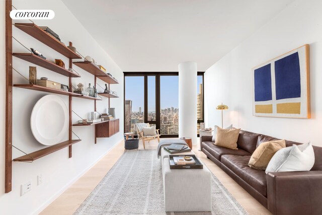 living room with visible vents, a view of city, light wood-style flooring, and a wall of windows