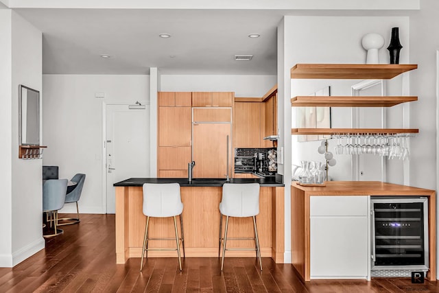 kitchen with paneled fridge, dark countertops, wine cooler, a peninsula, and dark wood-style flooring