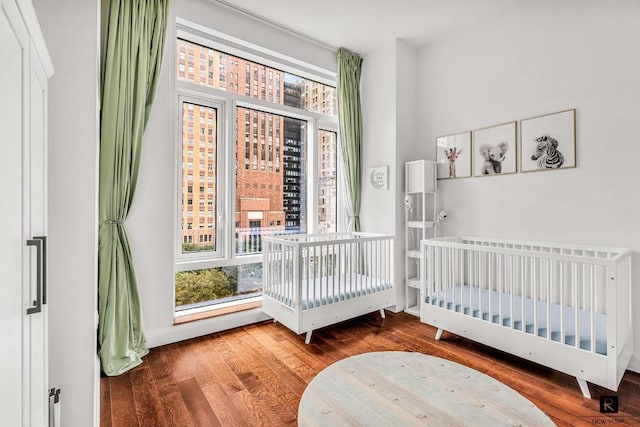 bedroom featuring a crib, baseboards, and wood finished floors