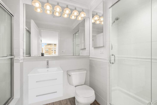 bathroom with a shower with shower door, tile walls, wood-type flooring, ornamental molding, and vanity