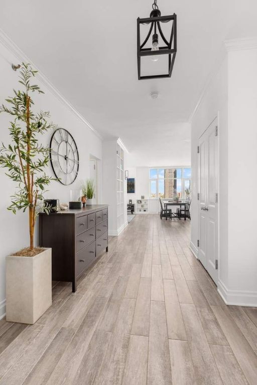 corridor featuring crown molding and light wood-type flooring