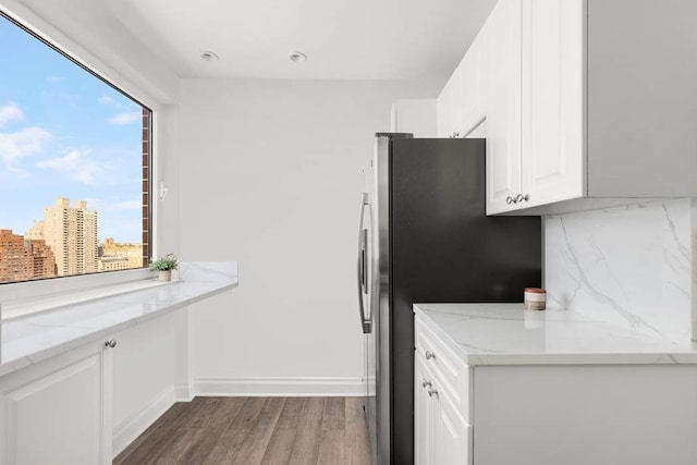 kitchen with a healthy amount of sunlight, backsplash, white cabinets, and light stone countertops