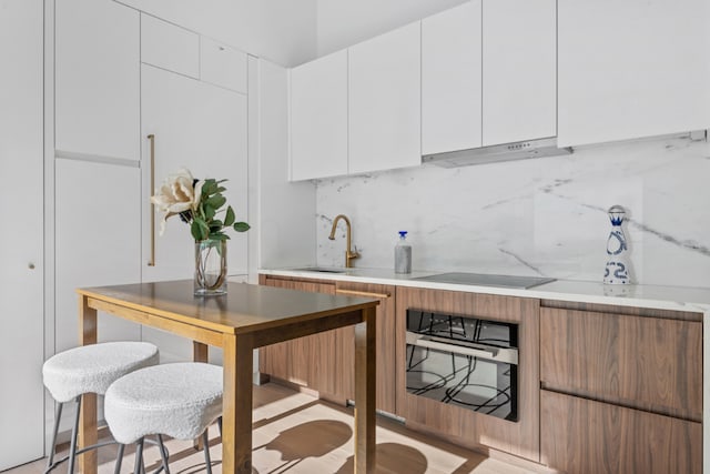 kitchen featuring tasteful backsplash, wall oven, and white cabinets