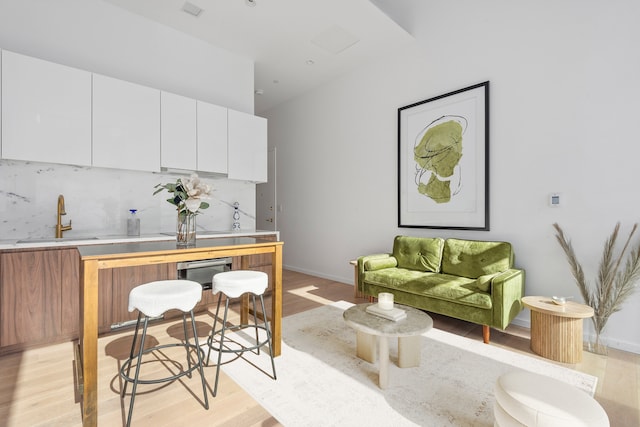 interior space featuring baseboards, light wood-style floors, a sink, and decorative backsplash