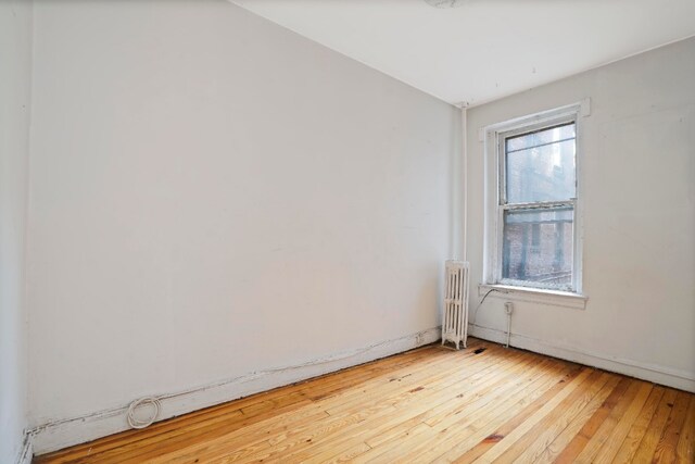 spare room featuring radiator and wood-type flooring