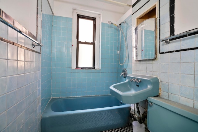 bathroom featuring tile walls, toilet, shower / bathing tub combination, and a sink