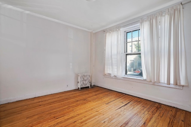 unfurnished room with crown molding, radiator, and light hardwood / wood-style floors