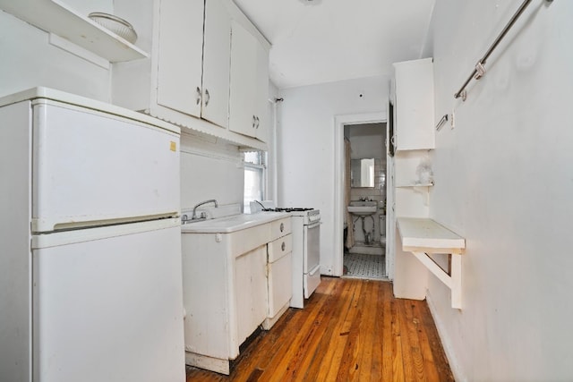 kitchen with sink, dark wood-type flooring, white cabinets, and white appliances