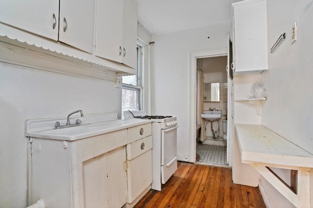 kitchen with dark hardwood / wood-style flooring, sink, white range with gas stovetop, and white cabinets