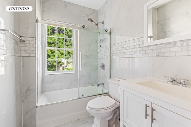 full bath with toilet, marble finish floor, shower / bath combination with glass door, tile walls, and vanity