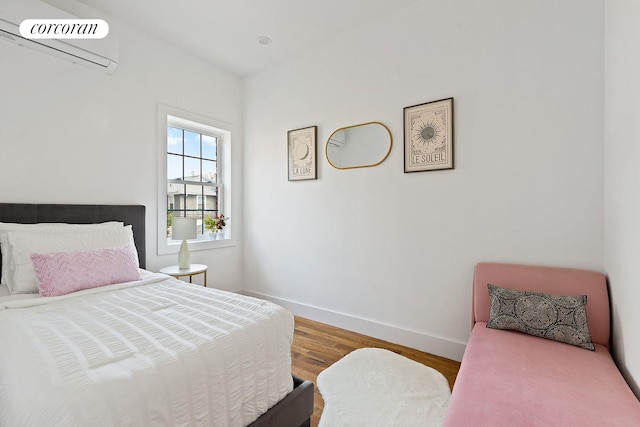 bedroom featuring baseboards, wood finished floors, and a wall mounted AC