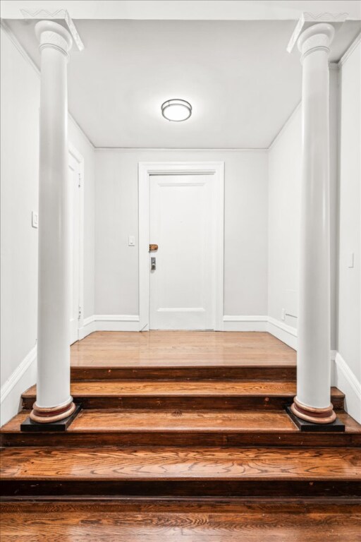 staircase with beam ceiling, ornamental molding, coffered ceiling, and hardwood / wood-style flooring