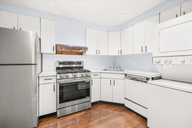 1 W 67th St Unit 2E, New York City, NY 10023 - kitchen featuring white appliances, stacked washer and clothes dryer, a sink, exhaust hood, and light countertops