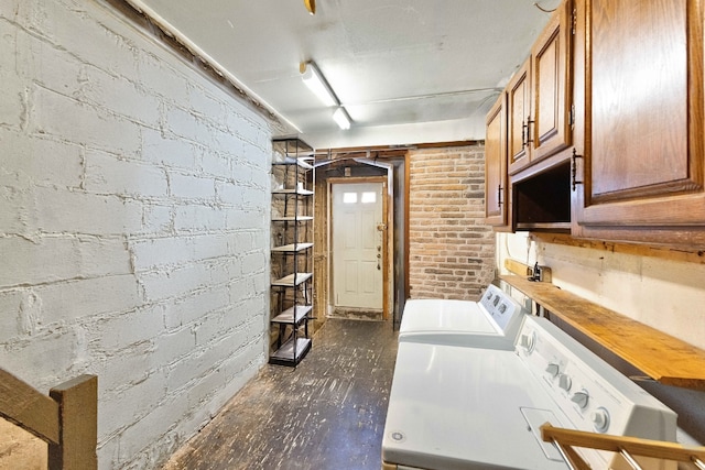 laundry room with cabinets, brick wall, and washer and clothes dryer