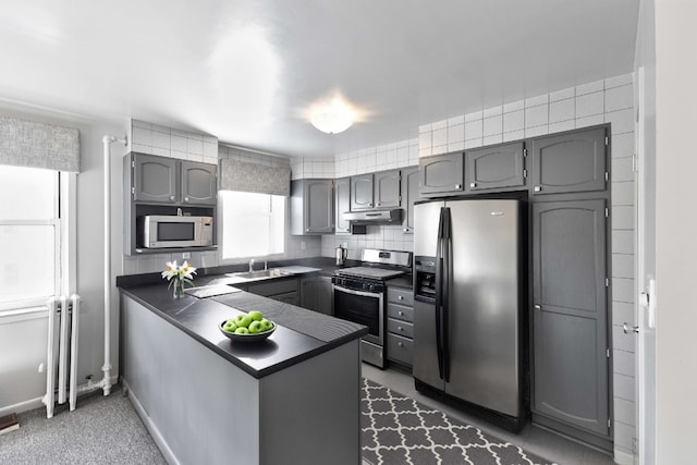 kitchen with stainless steel appliances, sink, backsplash, and kitchen peninsula