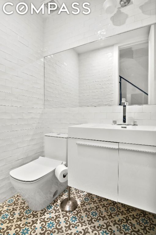 bathroom with toilet, vanity, and tile patterned floors