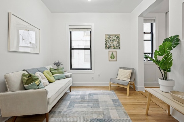 living area with a wealth of natural light, baseboards, and wood finished floors