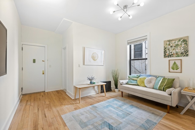 living room featuring a chandelier, light wood-style flooring, radiator, and baseboards