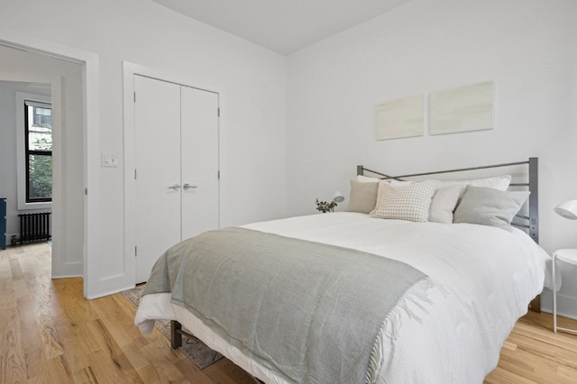 bedroom with radiator, a closet, and wood finished floors