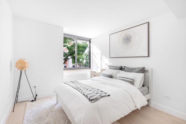 bedroom with light wood-type flooring and baseboards