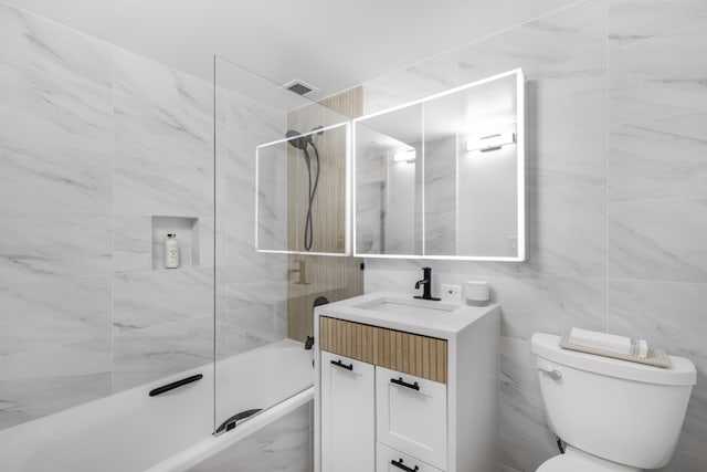 full bath featuring toilet, visible vents, vanity, tile walls, and tub / shower combination