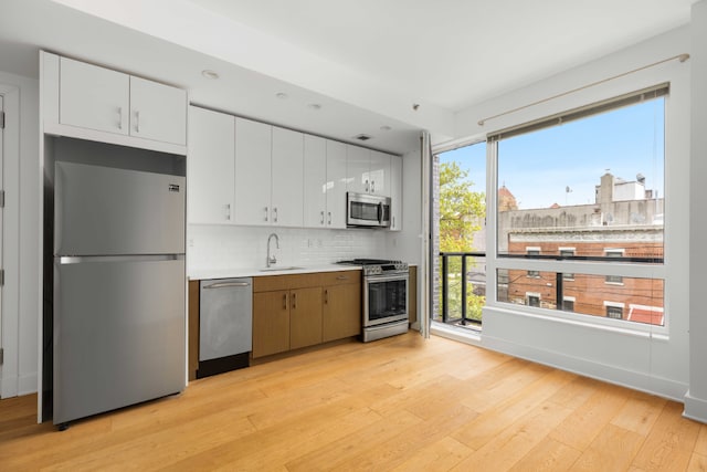 kitchen featuring appliances with stainless steel finishes, a wealth of natural light, sink, and white cabinets