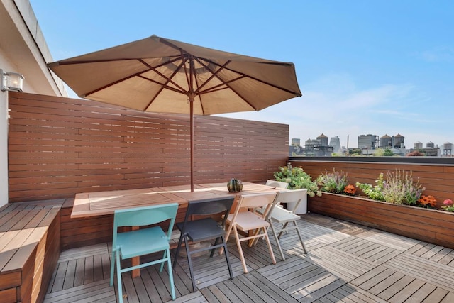 wooden deck with outdoor dining area and a city view