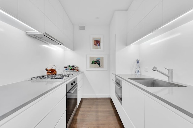 kitchen featuring light countertops, appliances with stainless steel finishes, white cabinetry, a sink, and modern cabinets