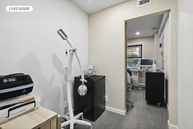 office area with visible vents, baseboards, and wood finished floors