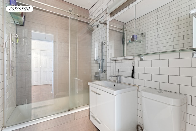 full bathroom featuring toilet, vanity, tile walls, tasteful backsplash, and shower / bath combination with glass door