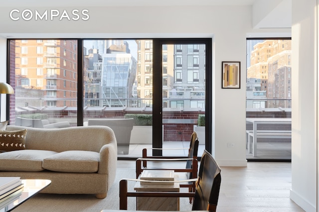 living area with a city view, baseboards, and wood finished floors