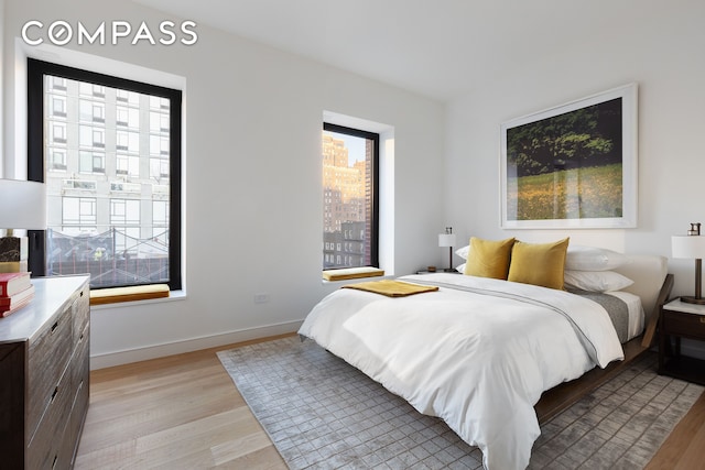 bedroom with baseboards, multiple windows, and light wood-style floors