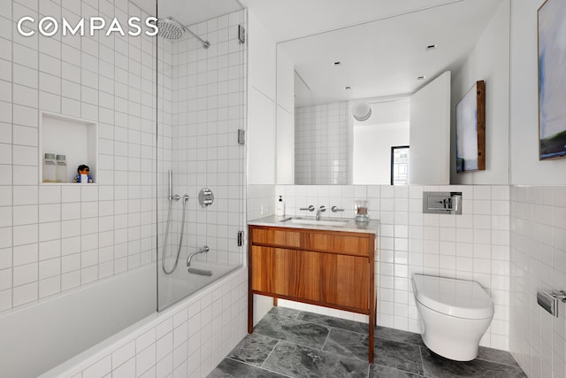 bathroom featuring toilet, tile walls, vanity, and tiled shower / bath