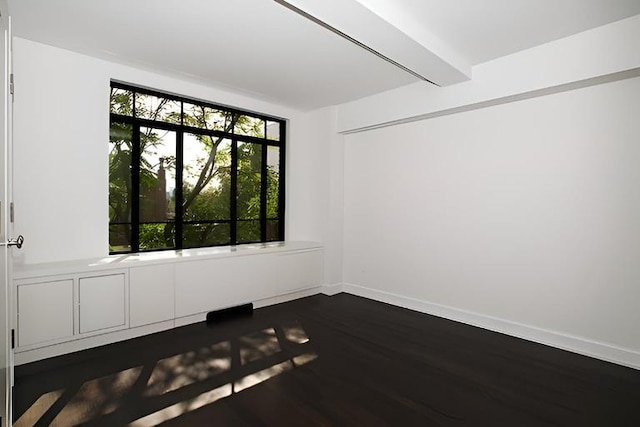 empty room featuring beamed ceiling and dark hardwood / wood-style floors