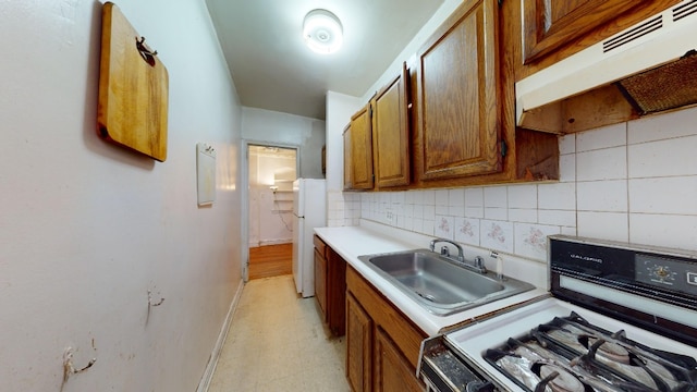 kitchen featuring backsplash, white appliances, and sink