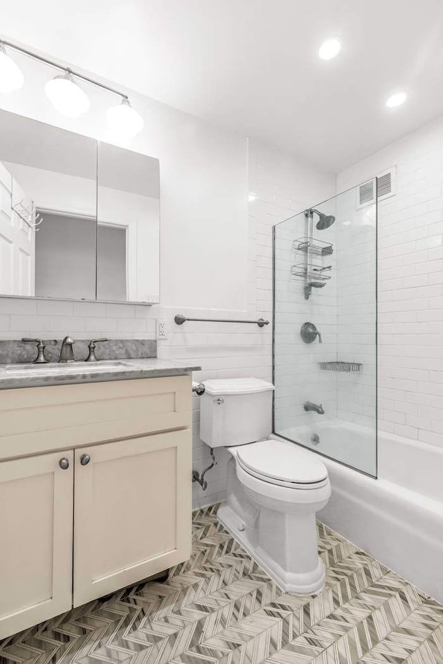 bathroom with vanity, visible vents, shower / bath combination, tile walls, and toilet