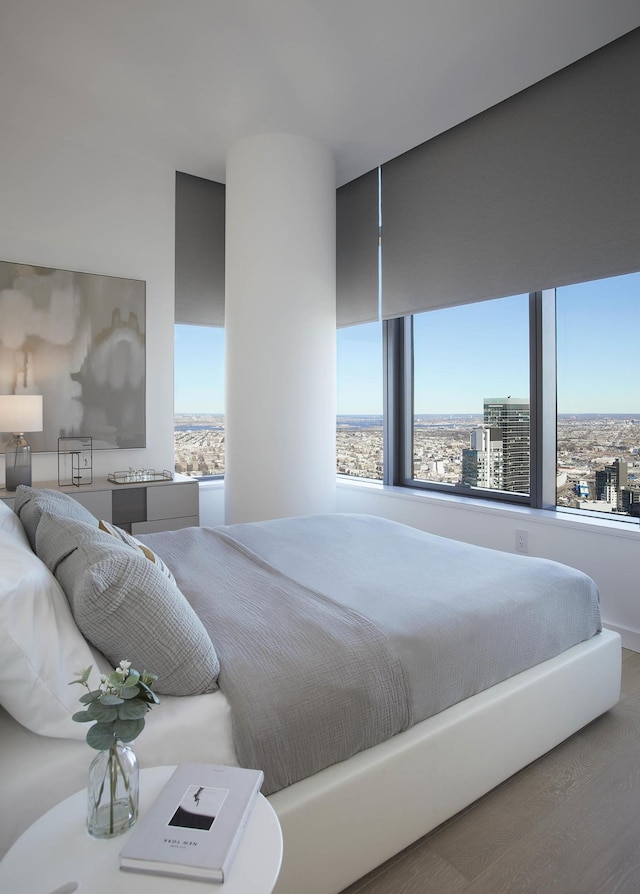 bedroom featuring a city view and wood finished floors