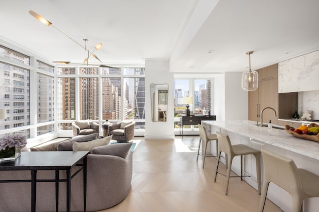 living room with sink, a notable chandelier, a wall of windows, and light parquet flooring