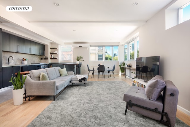 living room with light wood-style flooring, visible vents, baseboards, and a wall mounted air conditioner