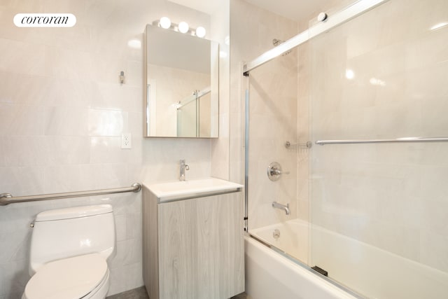 full bath featuring visible vents, toilet, combined bath / shower with glass door, vanity, and tile walls