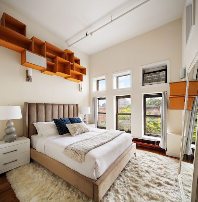 bedroom featuring a wall mounted AC, wood finished floors, and rail lighting