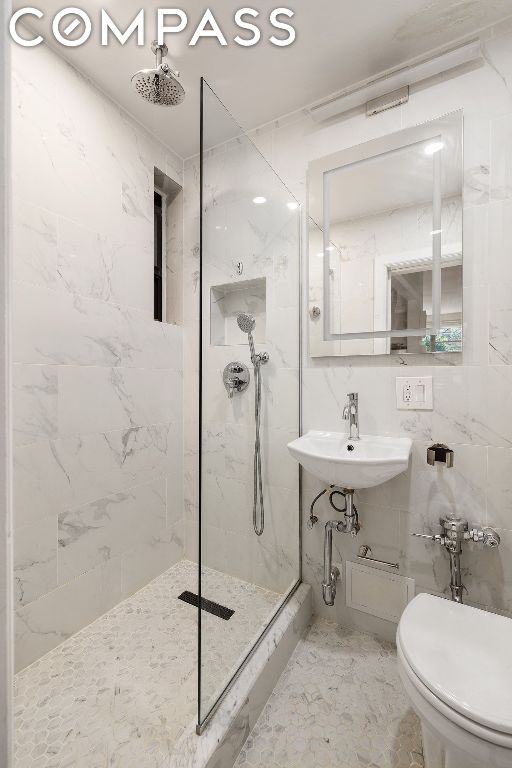 bathroom with tiled shower, toilet, and sink